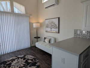 Sitting room with dark wood-style flooring and a wall unit AC