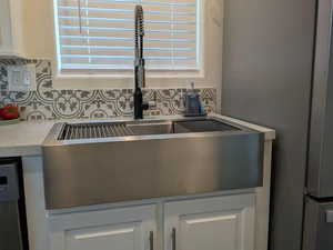 Details with dishwashing machine, a sink, white cabinetry, light countertops, and tasteful backsplash