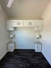 Laundry room featuring dark wood-type flooring, a skylight, and baseboards