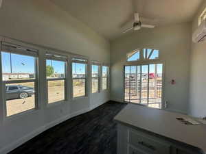 Unfurnished sunroom featuring a ceiling fan, vaulted ceiling, and a wall mounted AC