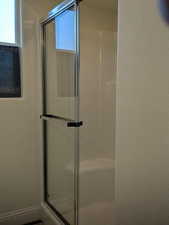 Full bathroom featuring a stall shower, plenty of natural light, and a textured wall