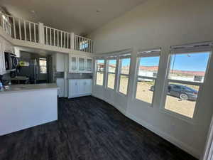 Kitchen with freestanding refrigerator, dark wood-style flooring, white cabinetry, and baseboards