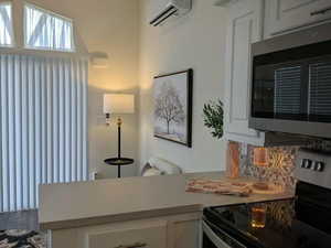 Kitchen featuring appliances with stainless steel finishes, a wall mounted air conditioner, and white cabinets