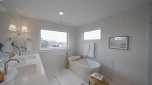 Bathroom with marble finish floor, a freestanding tub, a sink, and visible vents