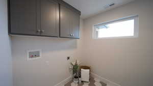 Clothes washing area with hookup for an electric dryer, washer hookup, visible vents, baseboards, and cabinet space