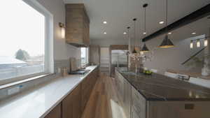Kitchen featuring a spacious island, hanging light fixtures, appliances with stainless steel finishes, dark wood-type flooring, and a sink