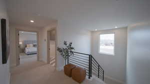 Hallway with recessed lighting, baseboards, light colored carpet, and an upstairs landing