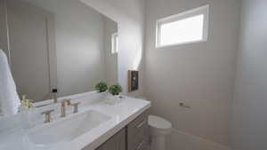 Bathroom with toilet, vanity, and baseboards