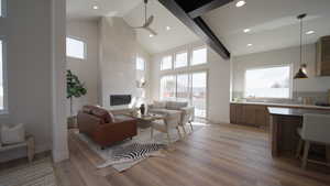 Living room featuring light wood-style floors, baseboards, high vaulted ceiling, and a tiled fireplace