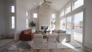 Living area with light wood finished floors, ceiling fan, baseboards, and high vaulted ceiling