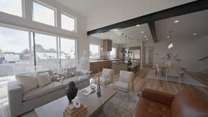 Living area featuring light wood-type flooring, beam ceiling, a high ceiling, and recessed lighting