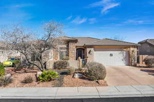 Single story home with a tile roof, stucco siding, an attached garage, stone siding, and driveway