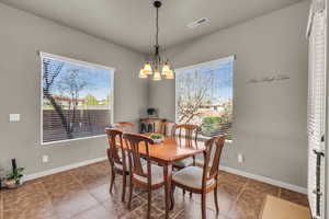 Dining space with baseboards, visible vents, and a notable chandelier