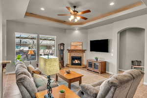 Living area with arched walkways, a tray ceiling, a fireplace, and visible vents