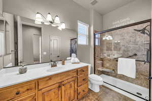 Full bathroom featuring toilet, a stall shower, visible vents, and vanity