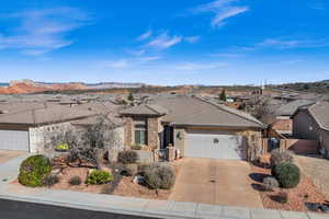 Ranch-style home featuring driveway, a garage, stone siding, a tiled roof, and a mountain view