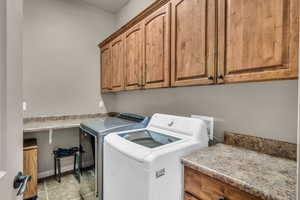 Laundry area with light tile patterned flooring, independent washer and dryer, cabinet space, and baseboards