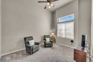 Living area with carpet flooring, ceiling fan, and baseboards