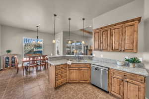 Kitchen featuring pendant lighting, brown cabinetry, a sink, dishwasher, and a peninsula