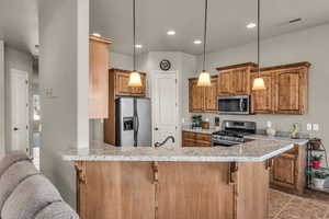 Kitchen featuring stainless steel appliances, a peninsula, and a kitchen bar