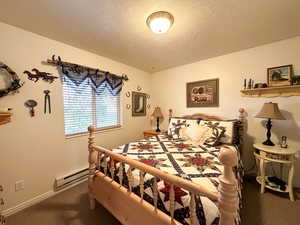 Carpeted bedroom with a baseboard radiator and a textured ceiling