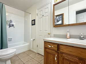 Full bathroom with shower / bathtub combination with curtain, vanity, tile patterned floors, and toilet