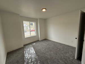 Unfurnished room with dark carpet, baseboards, and visible vents