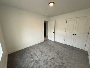 Unfurnished bedroom featuring carpet floors, baseboards, a closet, and visible vents