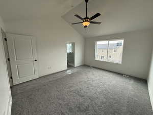 Carpeted empty room with a ceiling fan, baseboards, visible vents, and high vaulted ceiling
