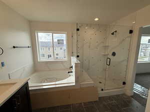 Full bathroom with plenty of natural light, a marble finish shower, a garden tub, and vanity