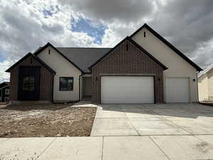 Single story home with an attached garage, driveway, stucco siding, and brick siding