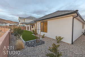 View of property exterior with a tiled roof, a lawn, a fenced backyard, and stucco siding