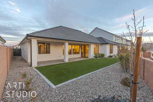 Back of house with a fenced backyard, a tile roof, a yard, stucco siding, and a patio area