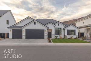 View of front of home with board and batten siding, decorative driveway, fence, and a garage