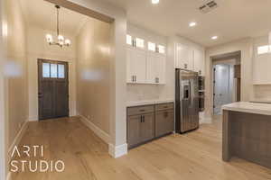 Kitchen featuring stainless steel appliances, light countertops, visible vents, glass insert cabinets, and white cabinets