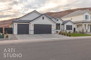 Modern farmhouse style home with board and batten siding, an attached garage, a tile roof, and a mountain view