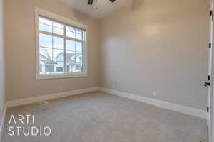 Unfurnished room featuring light carpet, baseboards, and a ceiling fan