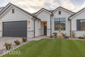 Modern inspired farmhouse with a tile roof, an attached garage, board and batten siding, a front yard, and driveway