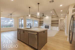 Kitchen with visible vents, hanging light fixtures, open floor plan, a sink, and an island with sink