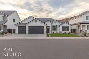 Modern inspired farmhouse with board and batten siding, decorative driveway, fence, and an attached garage