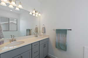 Bathroom featuring a sink, baseboards, and double vanity