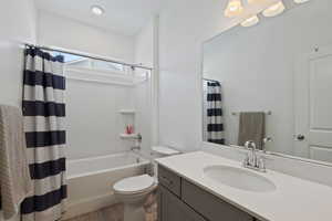 Full bath with wood finished floors, vanity, toilet, and shower / bath combo with shower curtain