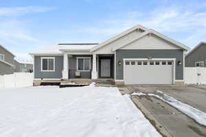 View of front of property featuring a garage, driveway, fence, and a porch