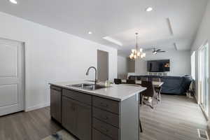 Kitchen with a sink, light stone countertops, dishwasher, an island with sink, and a raised ceiling