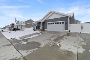 View of front of home featuring concrete driveway, an attached garage, a gate, fence, and a residential view