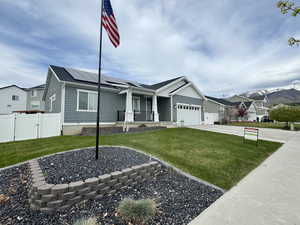 Ranch-style house featuring a gate, a porch, solar panels, and a front yard