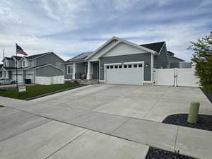 View of front of home featuring fence, a gate, concrete driveway, and a garage