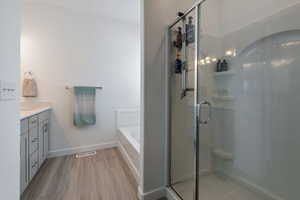 Full bath featuring visible vents, wood finished floors, vanity, and a shower stall