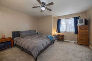 Bedroom featuring light carpet, baseboards, and a ceiling fan