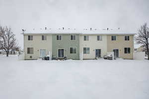 Snow covered rear of property featuring entry steps